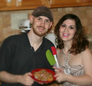 A happy male and female couple holding a plate of homemade cookies in the kitchen. 