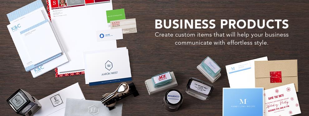 A wide range of business products, such as personalized notepads, ink stamps, an embosser, envelopes with labels, greeting cards, and business cards lay against a woodgrain background. Amidst the products, the words ''Business Products • Create custom items that will help your business communicate with effortless style.' are written in white.