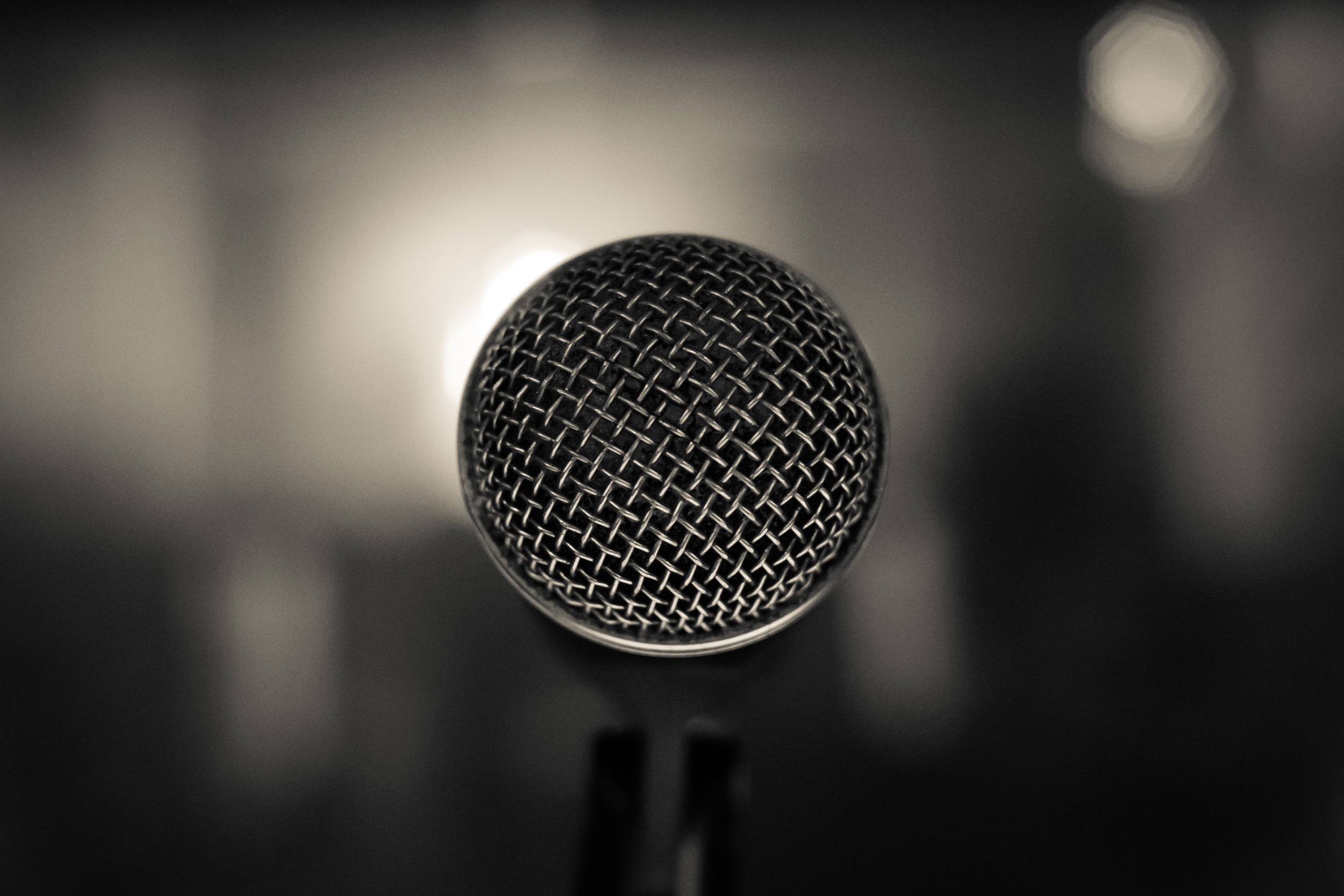 Close-up of a standing microphone with an out-of-focus black and white background.
