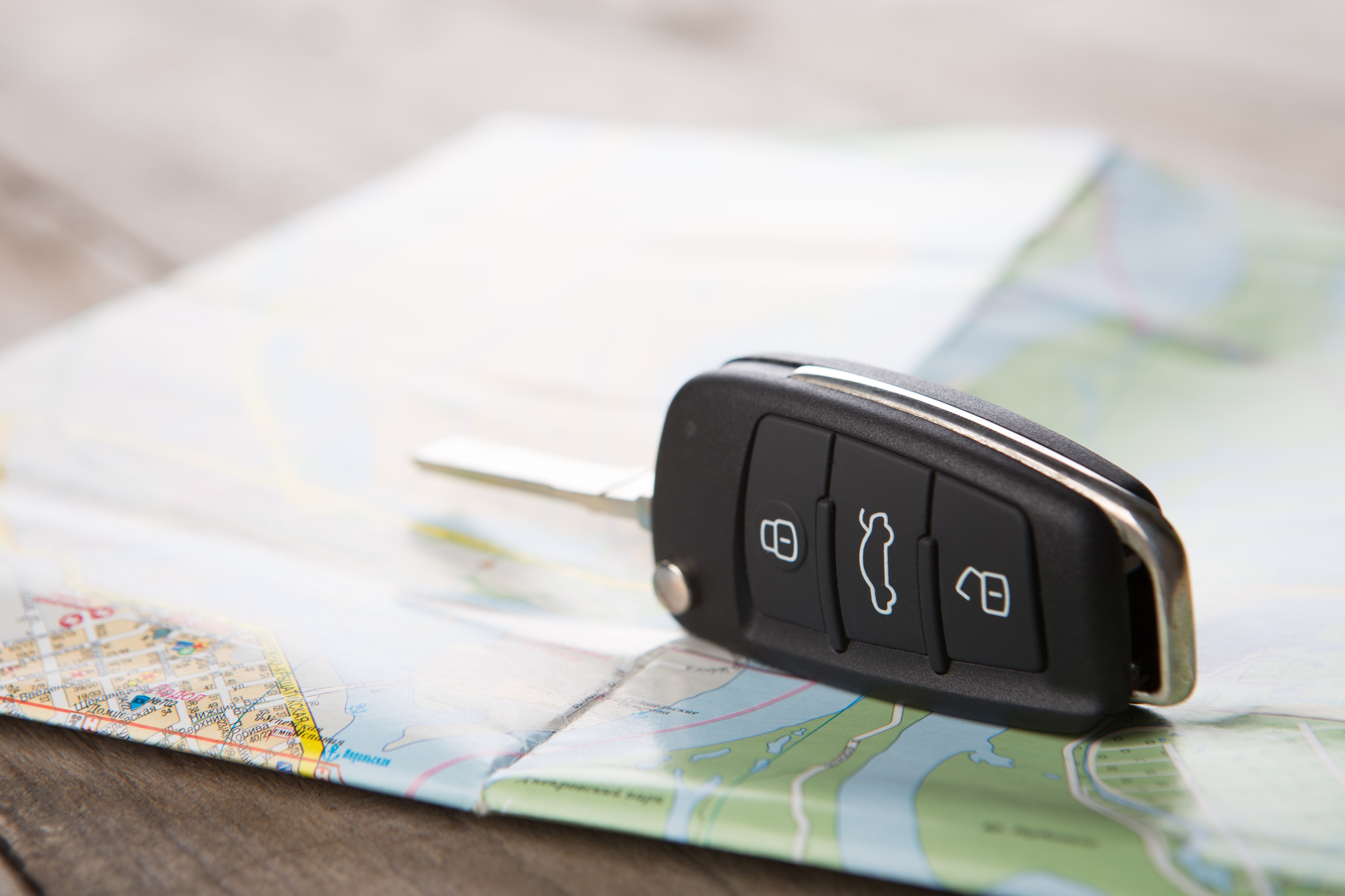 Car key fob sits atop a road map on a woodgrain background.