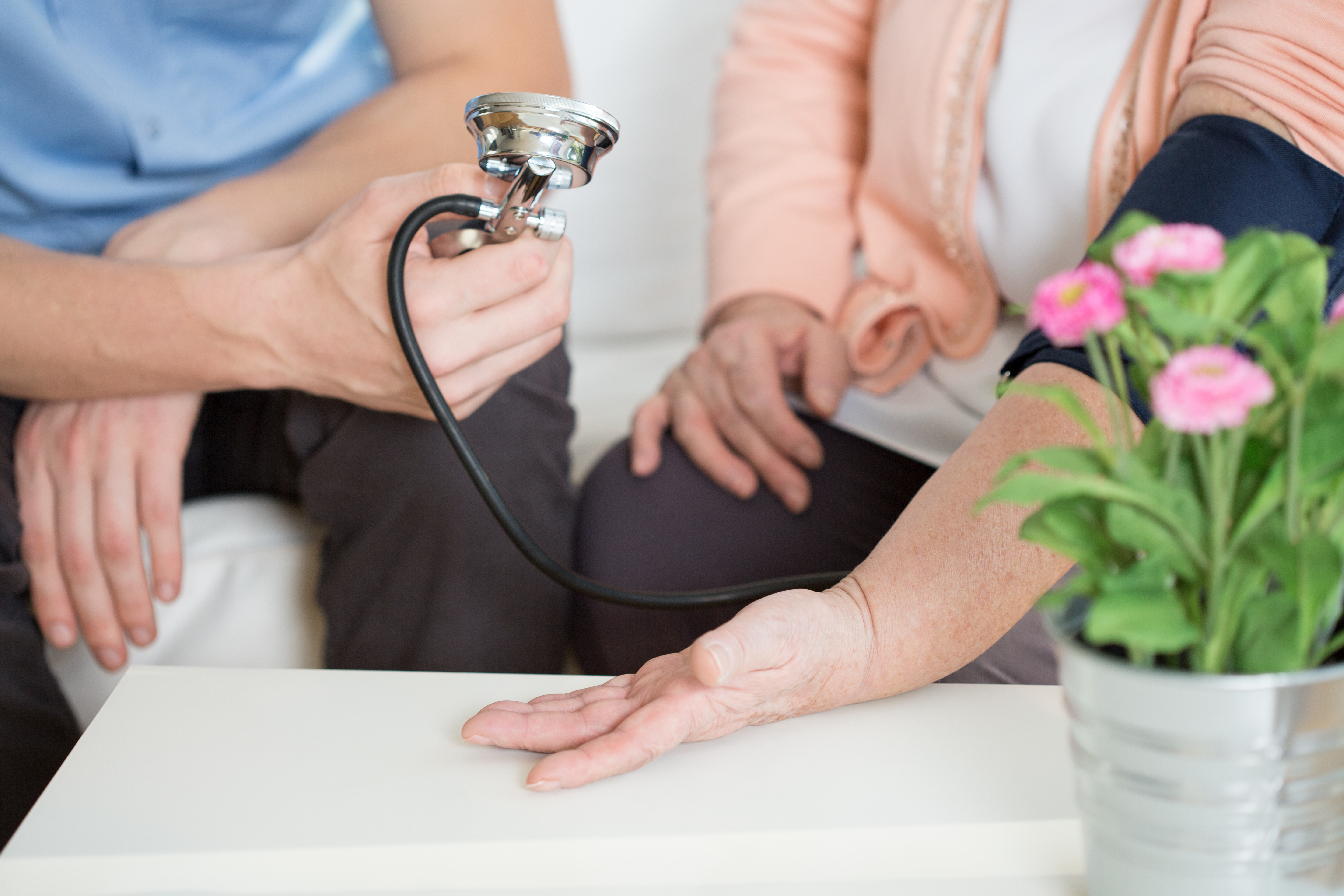 Close-up photograph of a male nurse taking and elderly female's blood pressure.