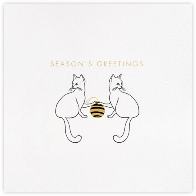 Two mischievous kittens playing with a black and gold Christmas tree ornament below a simple holiday message of 'Season's Greetings' in gold letters.