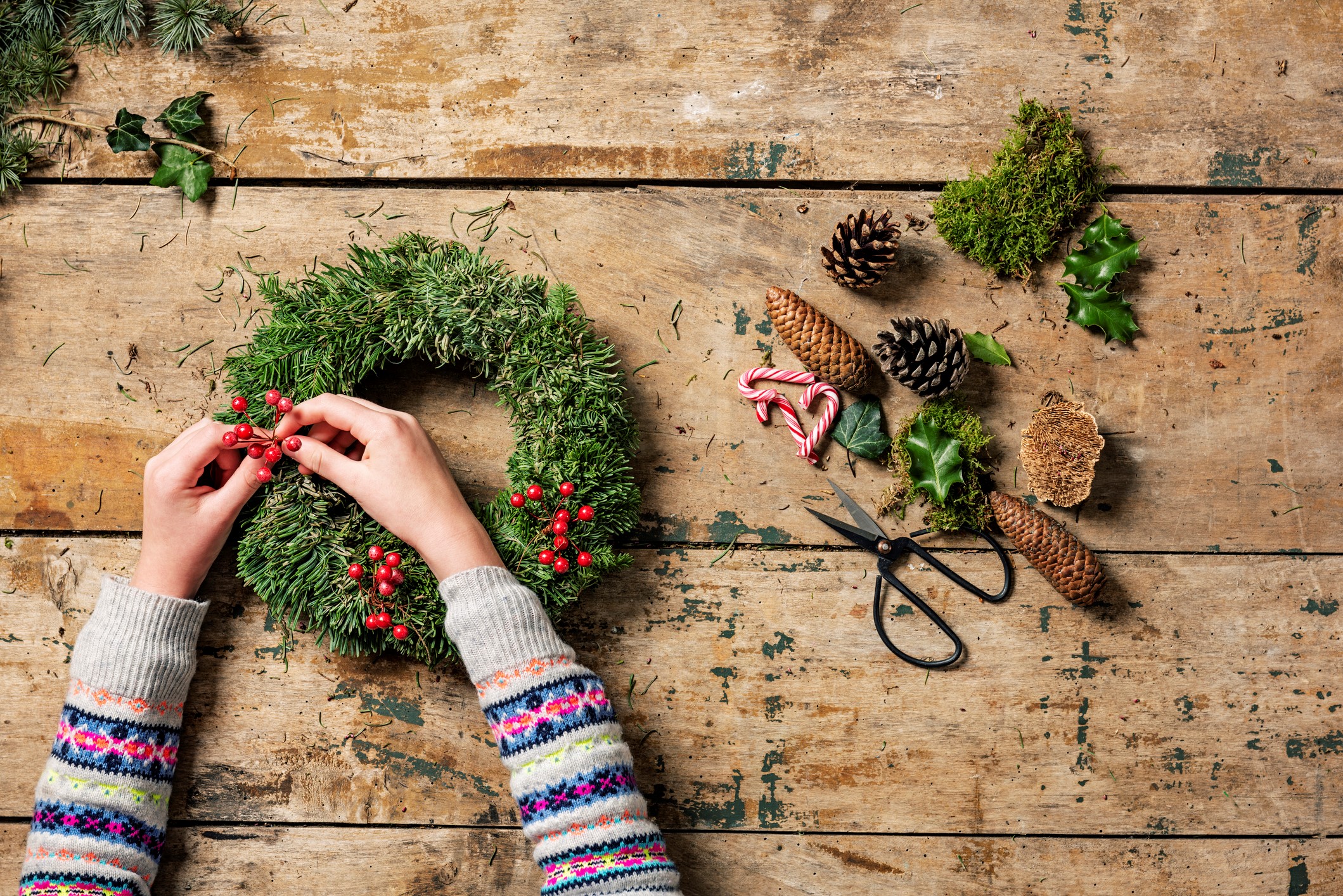 Overhead view of an arrangement of a Christmas wreath or garland being made by a teenage girl. Various tools and decorative pieces are laid out waiting to be used. Colour, horizontal with lots of copy space. Please see my other pictures in this series.