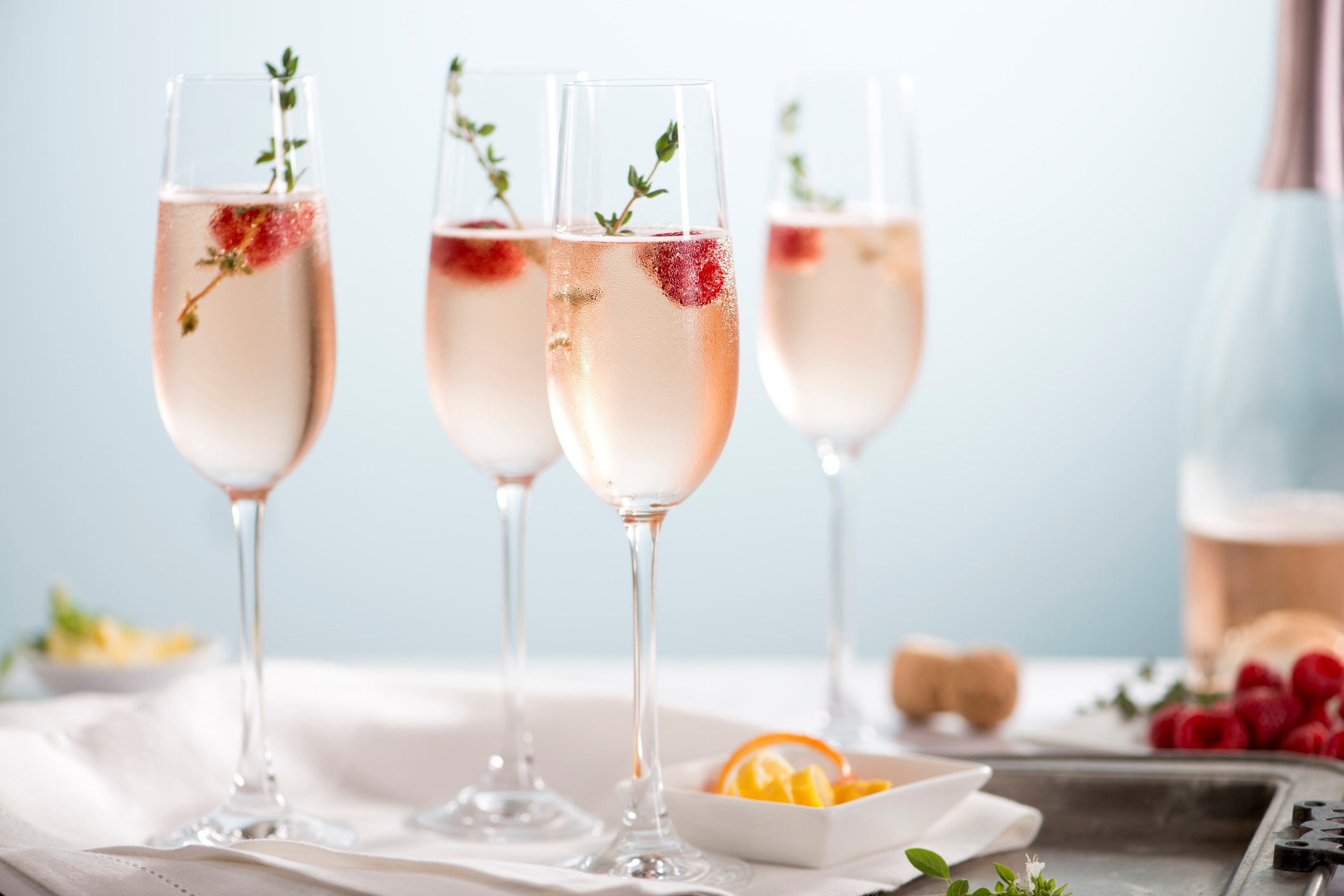 Flutes of pink rose champagne garnished with red raspberries and green thyme make for a festive cocktail gathering.