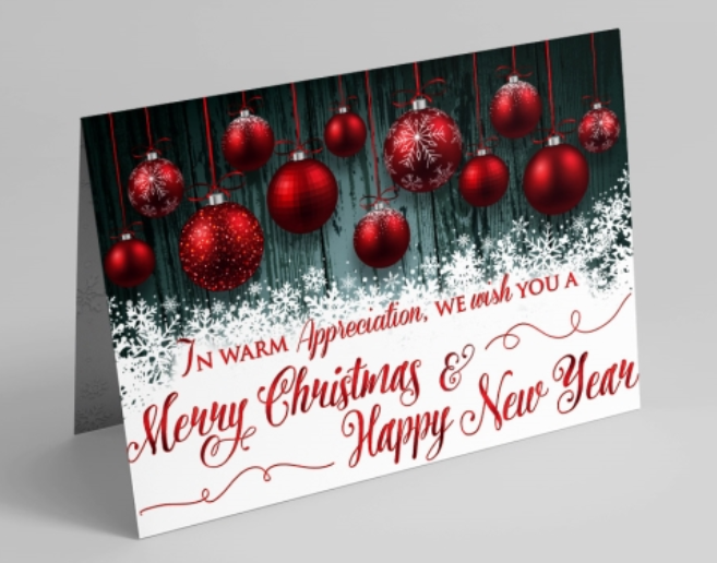 This card features gorgeous red ornaments with snowflake accents against a dark teal wood-grain background that rests above a pile of snowflakes. In the snowflakes, a message reads 'In Warm Appreciation, We Wish You A Merry Christmas & Happy New Year' in red letters. 