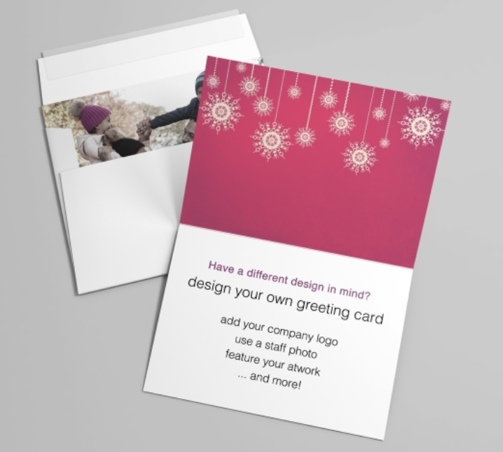 A an open greeting card with red, gold, and white holiday accents against an envelope with a photo card inside.