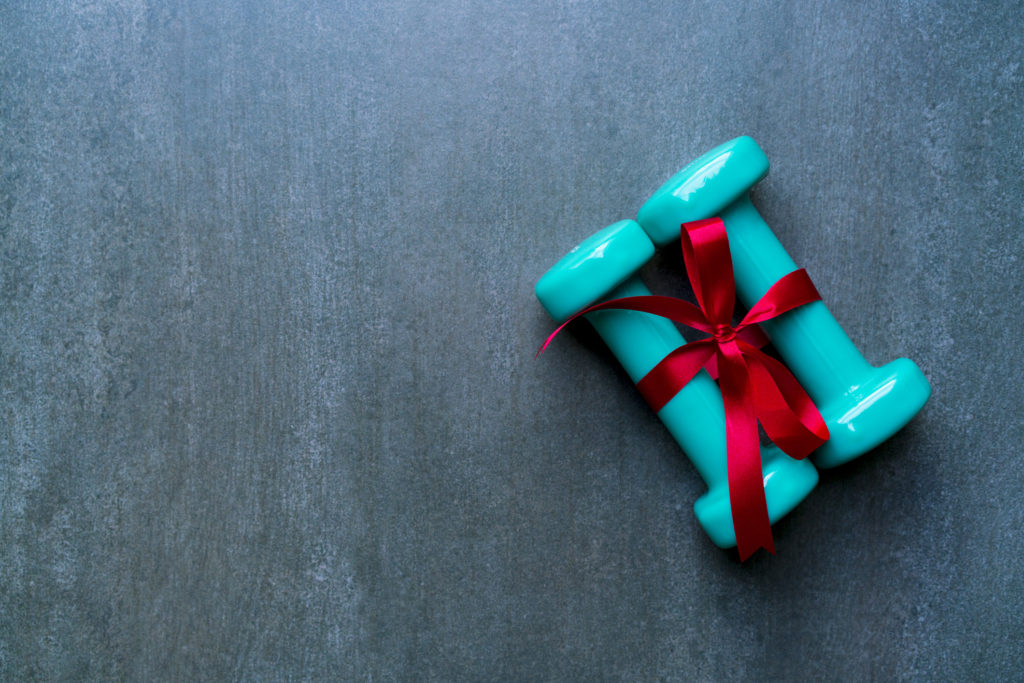 two green dumbbell with red gift bow on a black table background, sport and healthy concept