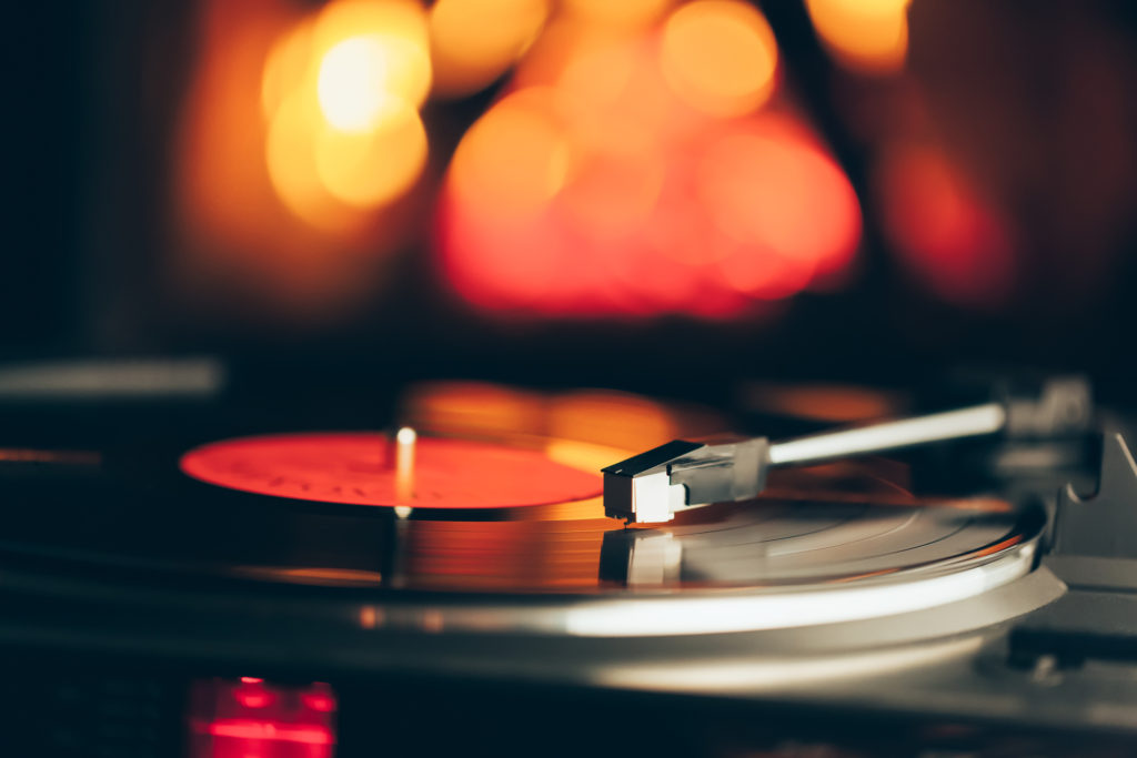 turntable with LP vinyl record against burning fire background, closeup view with headshell