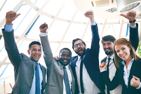 A group of people in business attire raising their fists in the air.